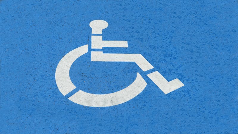 White wheelchair accessibility symbol painted on blue curb in a US parking lot